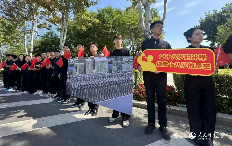 沈陽市人民廣場上，大學(xué)生們手持閱兵的圖片，告慰英烈。人民網(wǎng)記者 周頌雪攝